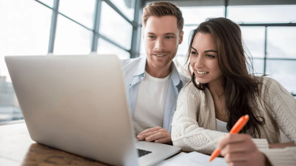 Młoda para wspólnie przegląda laptop i planuje budżet w jasnym wnętrzu