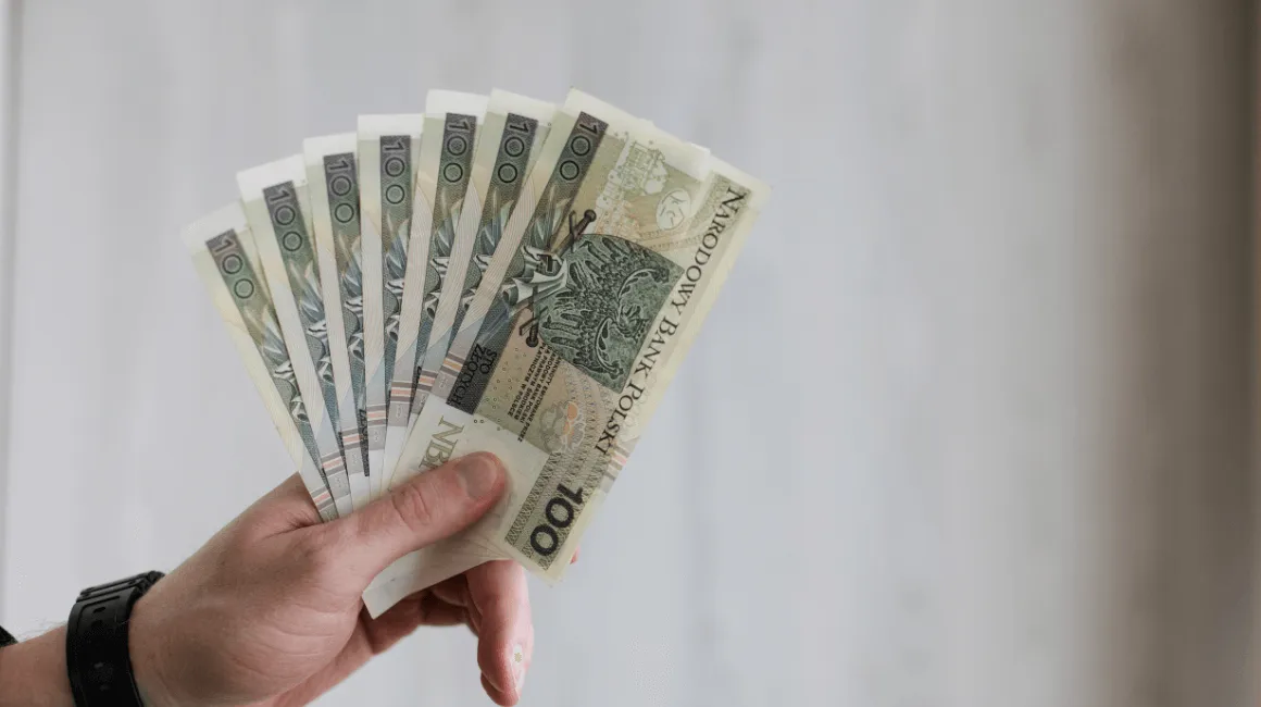 Osoba trzyma wachlarz banknotów 100 zł